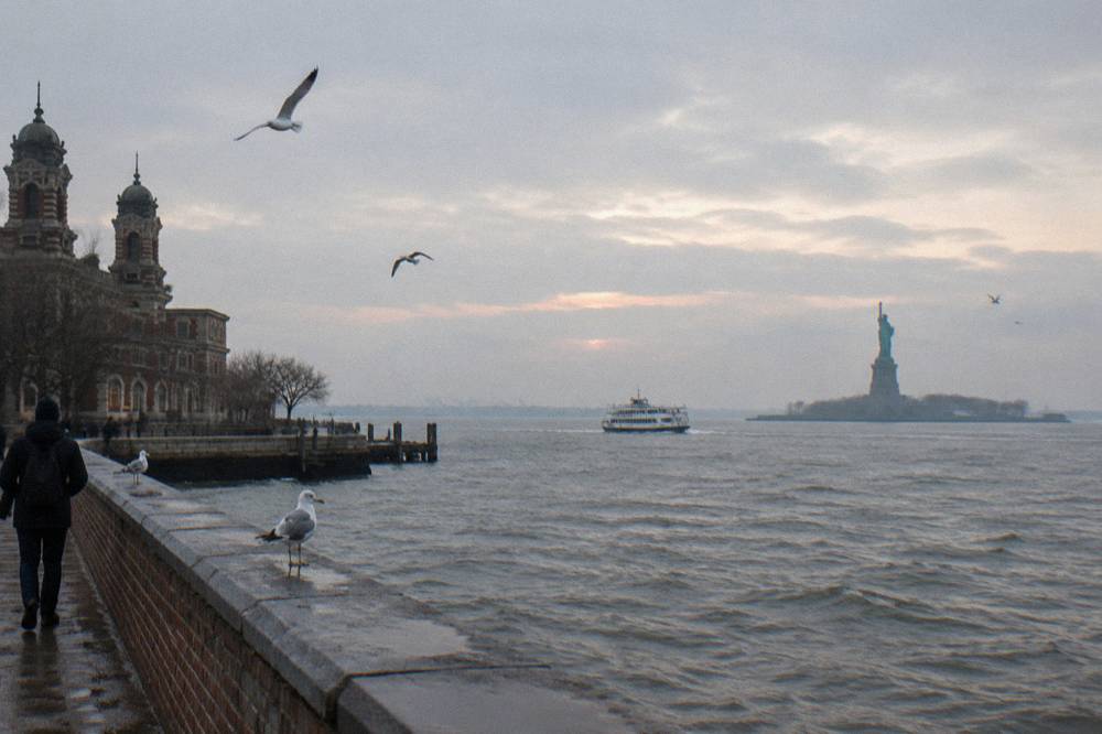 Small cruise boat passing the Statue of Liberty in New York Harbor